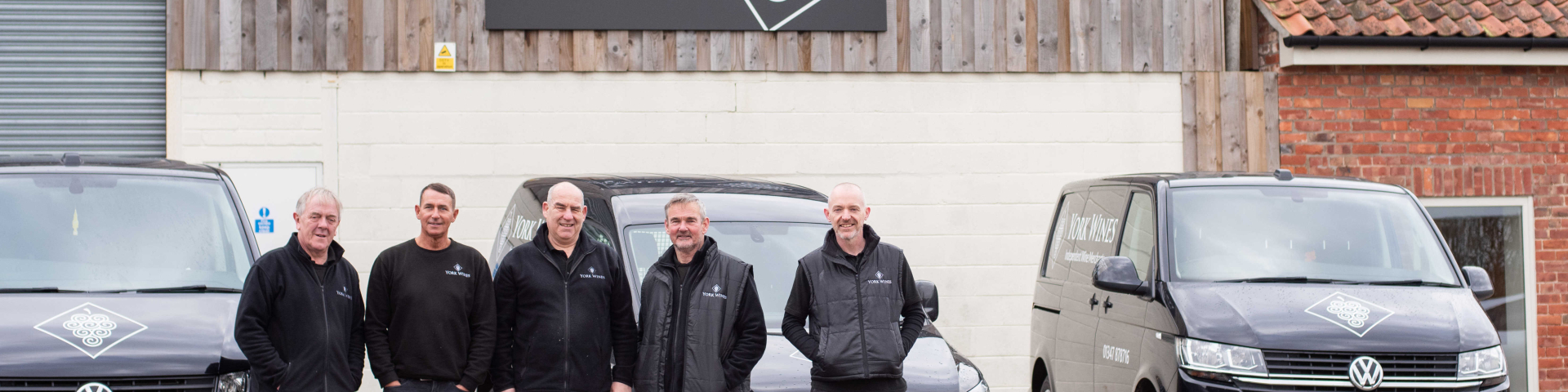 Warehouse and delivery team infront of warehouse and delivery vans